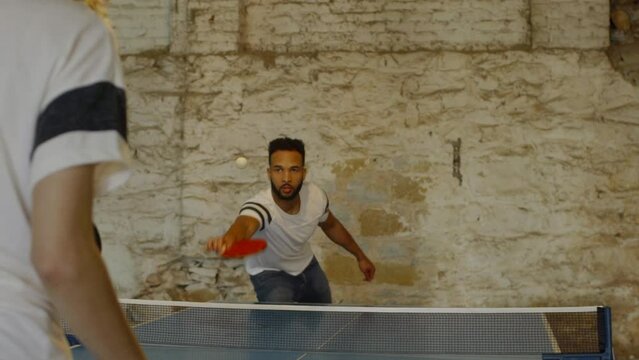 Handheld Shot Of Young Couple Playing Table Tennis In Old Building