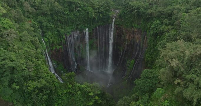 Aerial Forward Shot Of Famous Coban Sewu Waterfall On Rock Formations With Green Forest - Java, Indonesia