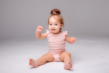 healthy baby girl in a pink bodysuit sits on a white background. space for text