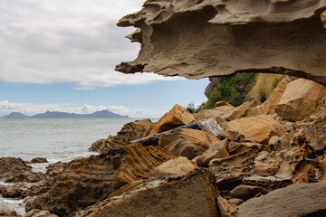 Rocky coastline with blue sea and an island on background, Auckland, New Zealand.
