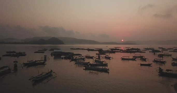 Drone shot of outriggers and fishing cages in sea against sky during sunset