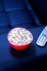 Bowl of popcorn on black couch in the evening