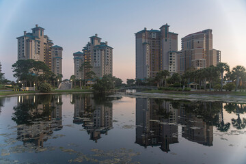 Reflective small lake with bridge near high-rise hotels apartments in Destin, Florida. Lakefront hotels or apartments against the sunset sky background.