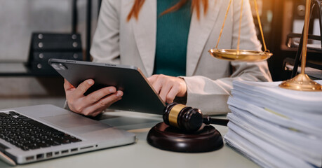 Fototapeta na wymiar justice and law concept.Male judge in a courtroom the gavel, working with smart phone and laptop and digital tablet computer on wood table in morning light .