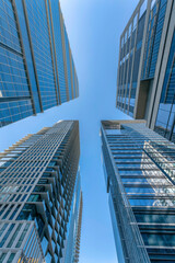 Austin, Texas- Four skyscraper buildings in a low angle view. View of building exterior with reflective glass wall facade against the blue sky background.