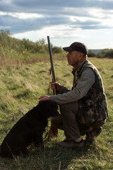 Mature man hunter with gun while walking on field with your dogs