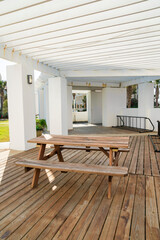 Destin, Florida- Shed near beach with white ceiling, wood planks flooring, and dining table. Wooden table with seats near the pillars on the left against the grass.