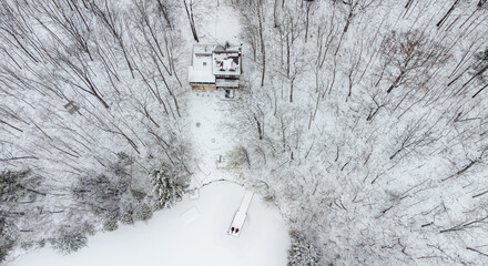 Aerial view of cottage and dock on a lake on snowy winter day.