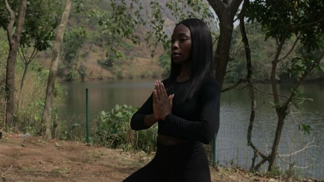 Profile shot of a lady in the tree pose by the lake, static medium shot
