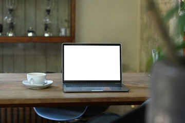 Mock up laptop and cup of coffee on rustic wooden table. Empty screen for your advertise design