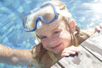 Adorable cheerful 5 years old girl in snorkel mask posing on poolside