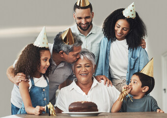 Family, birthday celebration and senior woman at a table with a cake, love and care in a house. Children, parents and grandparents together for a party to celebrate excited grandma with dessert