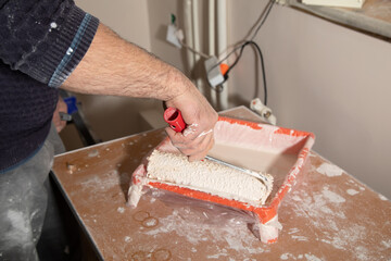 Male hand painting wall with paint roller.