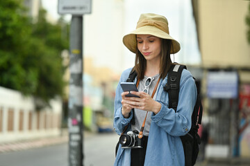 Pretty female traveler with backpack on holiday vacation trip in Thailand and using mobile phone for searching direction