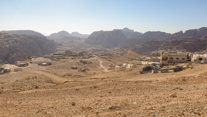 Desert landscape view of rural village town with long winding road and mountainous backdrop in Jordan, Middle East