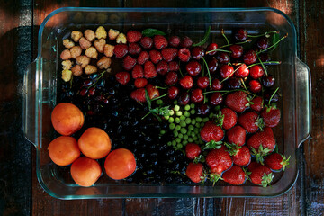 Assorted fresh seasonal fruits and berries: strawberries, apricots, cherries, mulberry, raspberries...