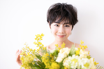 ウェディングや前撮り美容イメージに使えそうなミモザの花束を抱える可愛らしい女性