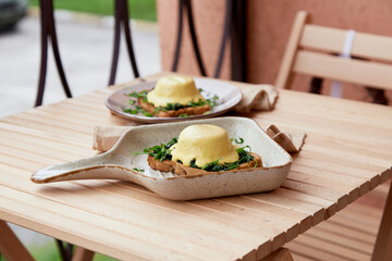 Eggs benedict with plant-based sauce, sourdough bread, tofu, young onion, greens, pea sprouts. Vegan dish. Healthy breakfast for two person.