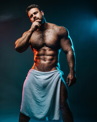 Big muscled man in white towel. Handsome hunk posing is studio. Naked male model with muscles and...