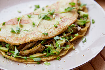 Close up of alternative vegan pancakes filled with mushrooms, pea sprouts, avocado. Healthy breakfast