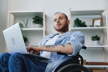 Man in wheelchair freelancer working at laptop at home smile, working online, social networks and startup, copy space, social integration, health concept man with disabilities, real person