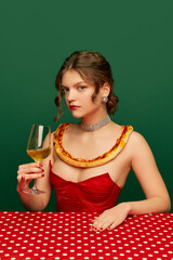 Tasting wine. Young stylish beautiful girl with pizza crust on her shoulders sitting at table over...
