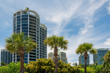 Fototapeta premium Condominiums under the clouds in sky in Miami, Florida. There are trees at the front of high-rise residential buildings with modern glass exterior.