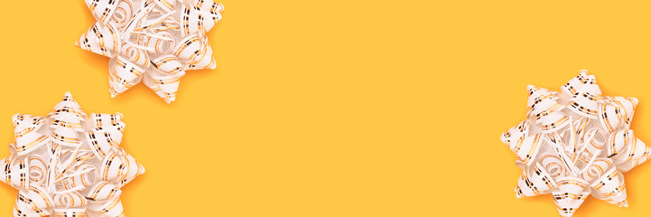 Banner with gold colored ribbon bows scattered on a yellow background.