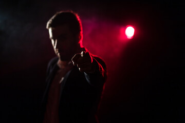 Photo of man showing thumb up on dark background with pink light.