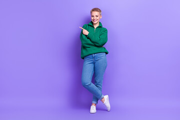 Fototapeta premium Full length photo of confident adorable lady wear green sweater pointing empty space isolated violet color background