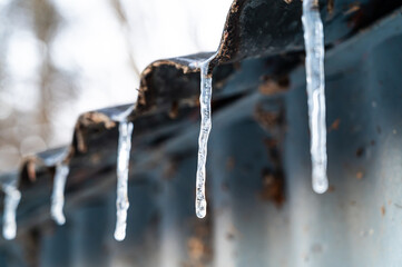 Ice candles protruding from a roof. Cold wave and winter temperatures.
