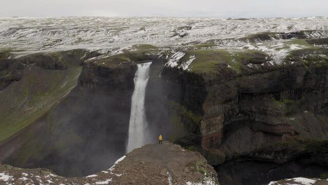 Aerial: One person wearing yellow jacket, looking at Haifoss waterfall