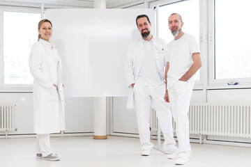 portrait of three doctors, standing in front of a whiteboard