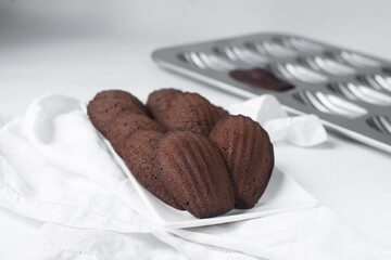Chocolate madeleines on a ceramic plate, plain chocolate madeleine cake or cookies