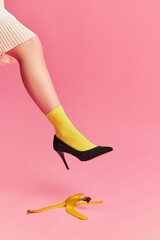 Creative colorful portrait of female leg in bright yellow socks and banana peel over pink...