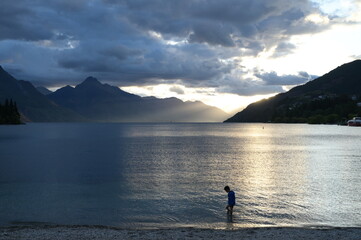 A boy standing along the lake