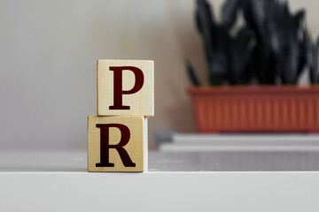 The word 'PR' written on wood cube. Public relation marketing business concept.