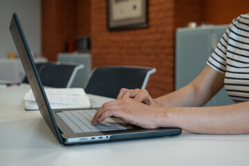 Pregnant woman sitting at desk with laptop in office. Real person in real situation.