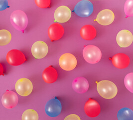 Pattern made of colorful balloons on purple background. Flat lay party concept.