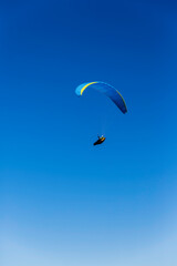 Paraglider flying against a blue sky on a sunny day