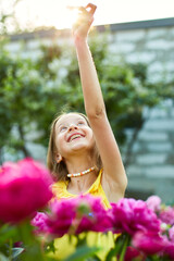 Happy little girl with braces in the garden in bushes of peonies