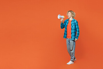 Fototapeta premium Full body young blond fun man wear blue shirt orange t-shirt hold in hand megaphone scream announces discounts sale Hurry up isolated on plain red background studio portrait. People lifestyle concept.