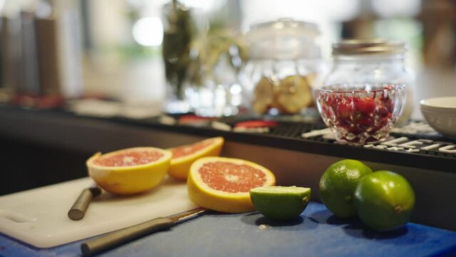 cut-up oranges and limes, with a bowl of raspberries in the back, handheld shot
