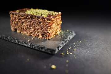 Chocolate cake with walnuts and pistachio isolated on black background. Pastry from homemade bakery