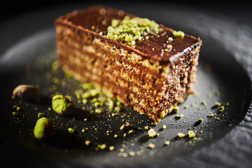 Chocolate cake with walnuts and pistachio isolated on black background. Pastry from homemade bakery