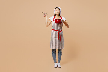 Full body young housewife housekeeper chef baker latin woman wear apron toque hat sniff smell scent...
