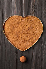 Cocoa in a box in the shape of a heart and sweets on a dark background top view copy space for text.