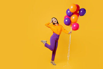 Fototapeta na wymiar Full body cheerful side profile view happy fun young woman wear casual clothes celebrating hold head bunch of balloons posing isolated on plain yellow background. Birthday 8 14 holiday party concept.