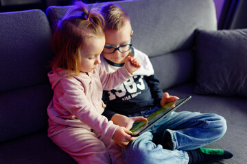 Danya's older brother teaches her younger sister how to use a tablet.