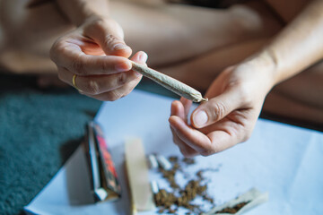 women cannabis holding a roll joint of marijuana in the room ,Drugs narcotic concept. Legal Marijuana.